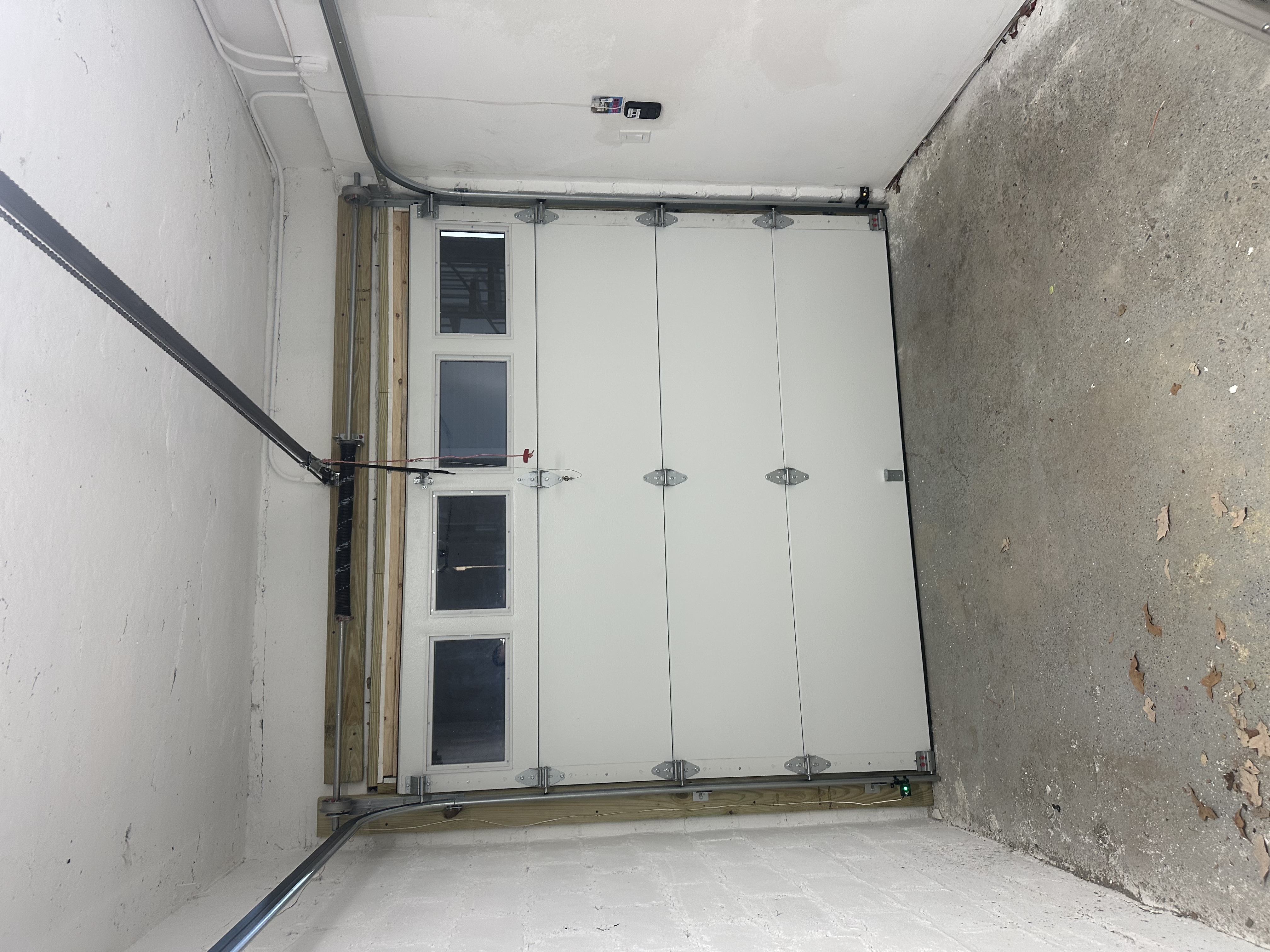 Completed white insulated garage door installation inside a finished garage